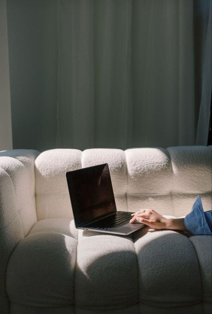 A laptop open on a soft couch in a quiet living room